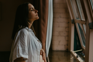 ambivalent pregnancy; pregnant woman staring outside of window