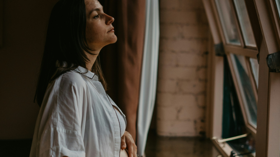 ambivalent pregnancy; pregnant woman staring outside of window