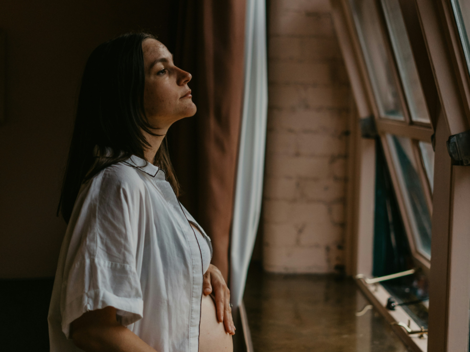 ambivalent pregnancy; pregnant woman staring outside of window